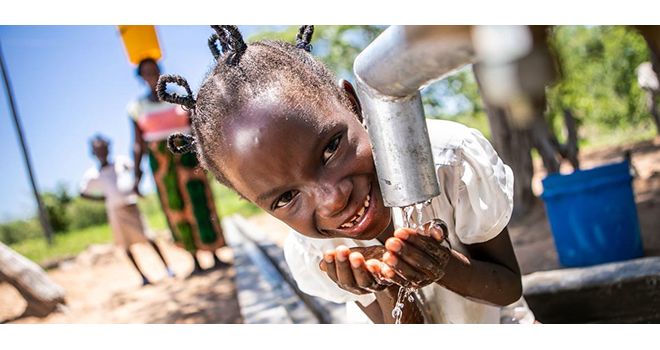 Une fillette au Zimbabwe boit de l'eau propre et salubre un puits réhabilité avec le soutien de l'ONU. Photo : Unicef, Karin Schermbrucker