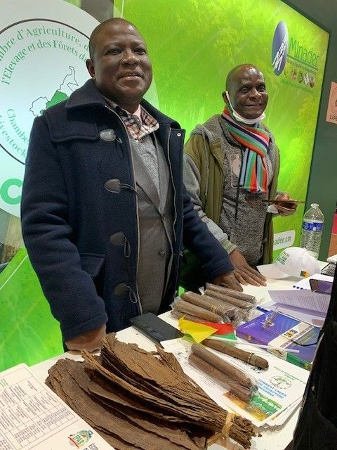 Le nouveau président de la chambre d’agriculture du Cameroun, M. Martin Mindjos (veste bleue), a conduit une forte délégation des producteurs au SIA. Ici il présente les cigares made in Cameroon. Le nouveau président de la chambre d’agriculture du Cameroun, M. Martin Mindjos (veste bleue), a conduit une forte délégation des producteurs au SIA. Ici il présente les cigares made in Cameroon. © Silas Bayebane