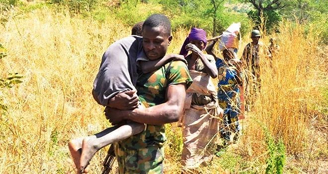 Des paysannes fuient leurs terres, aidées par des militaires, au nord du pays. Photo : Daouda Aliyou